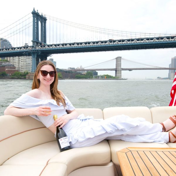 woman with champagne during private boat charters in NYC with the Brooklyn Bridge in the background