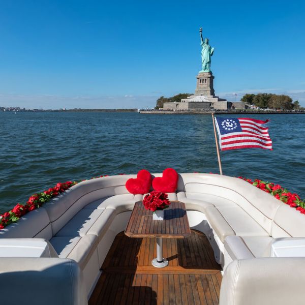 romantic boat tours with red pillows, flower garlands, American flag, and the Statue of Liberty