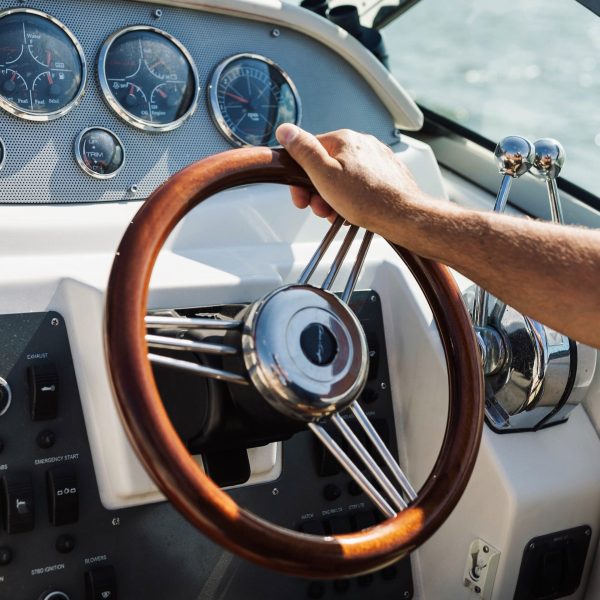 brown steering wheel and captain's arm on a boat rental New York