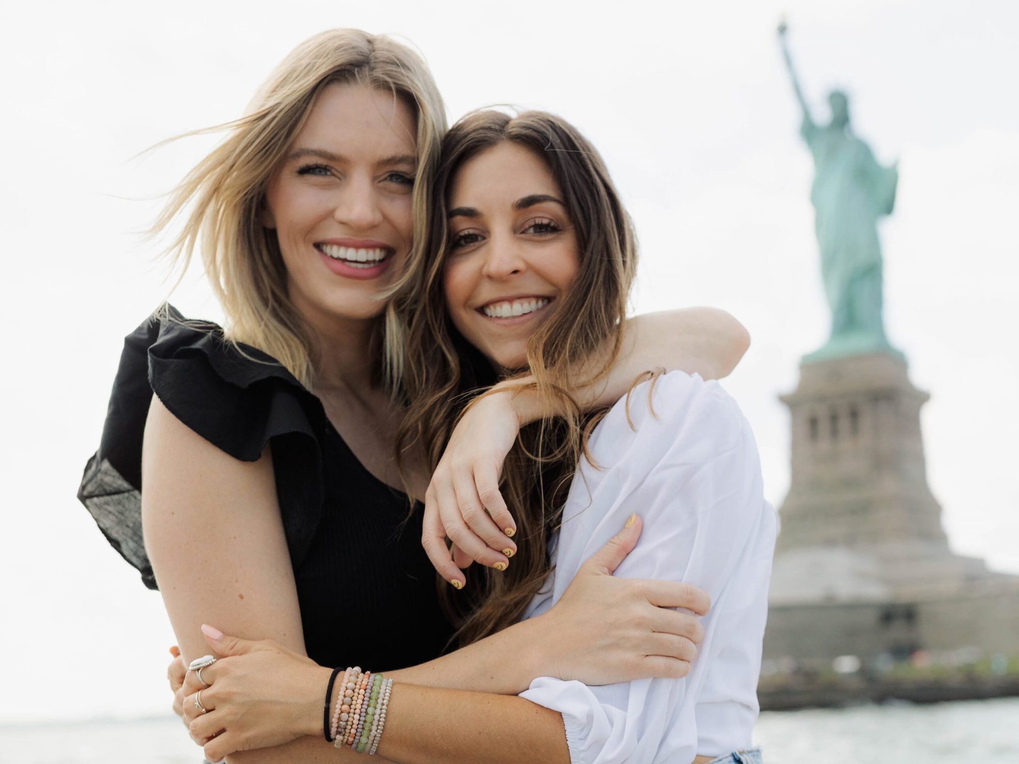 two women by the Statue of Liberty during a couples boat ride NYC