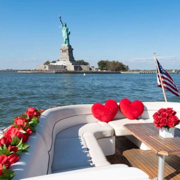 romantic yacht rental in NYC with heart pillows and flowers by the Statue of Liberty