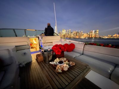 Yacht charter with champagne, food platter and red roses overlooking the NYC skyline in the evening.