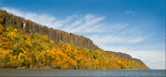 Cliff overlooking a river with autumn trees and blue sky.
