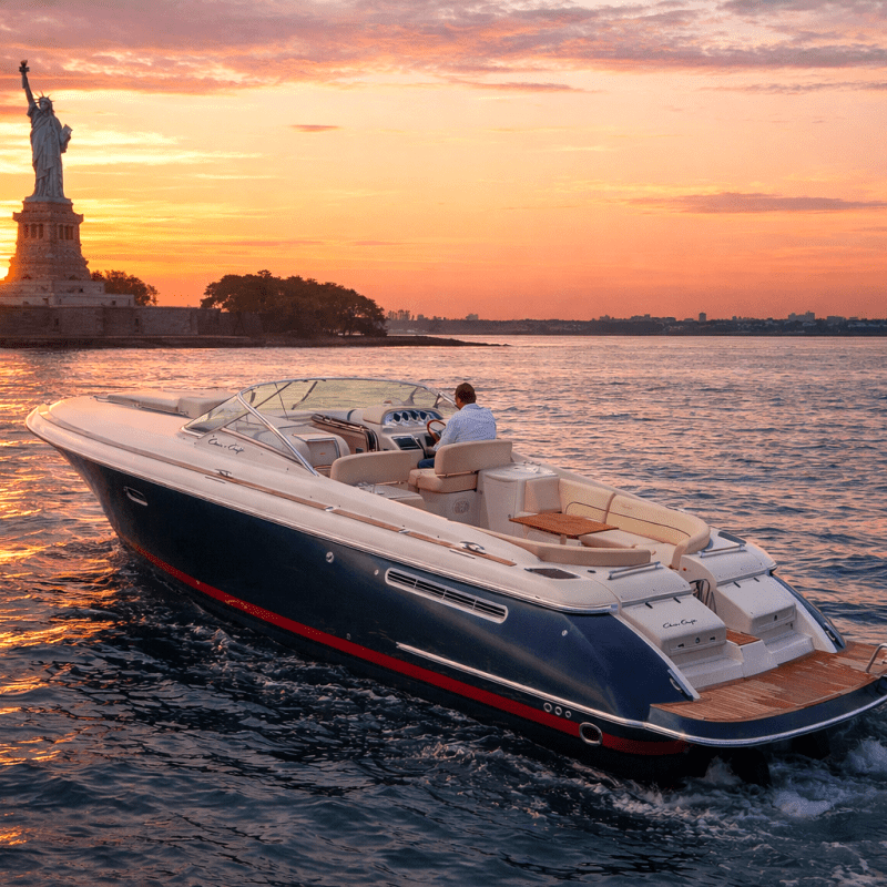 Private sunset cruise near Statue of Liberty with orange sky and reflective water.