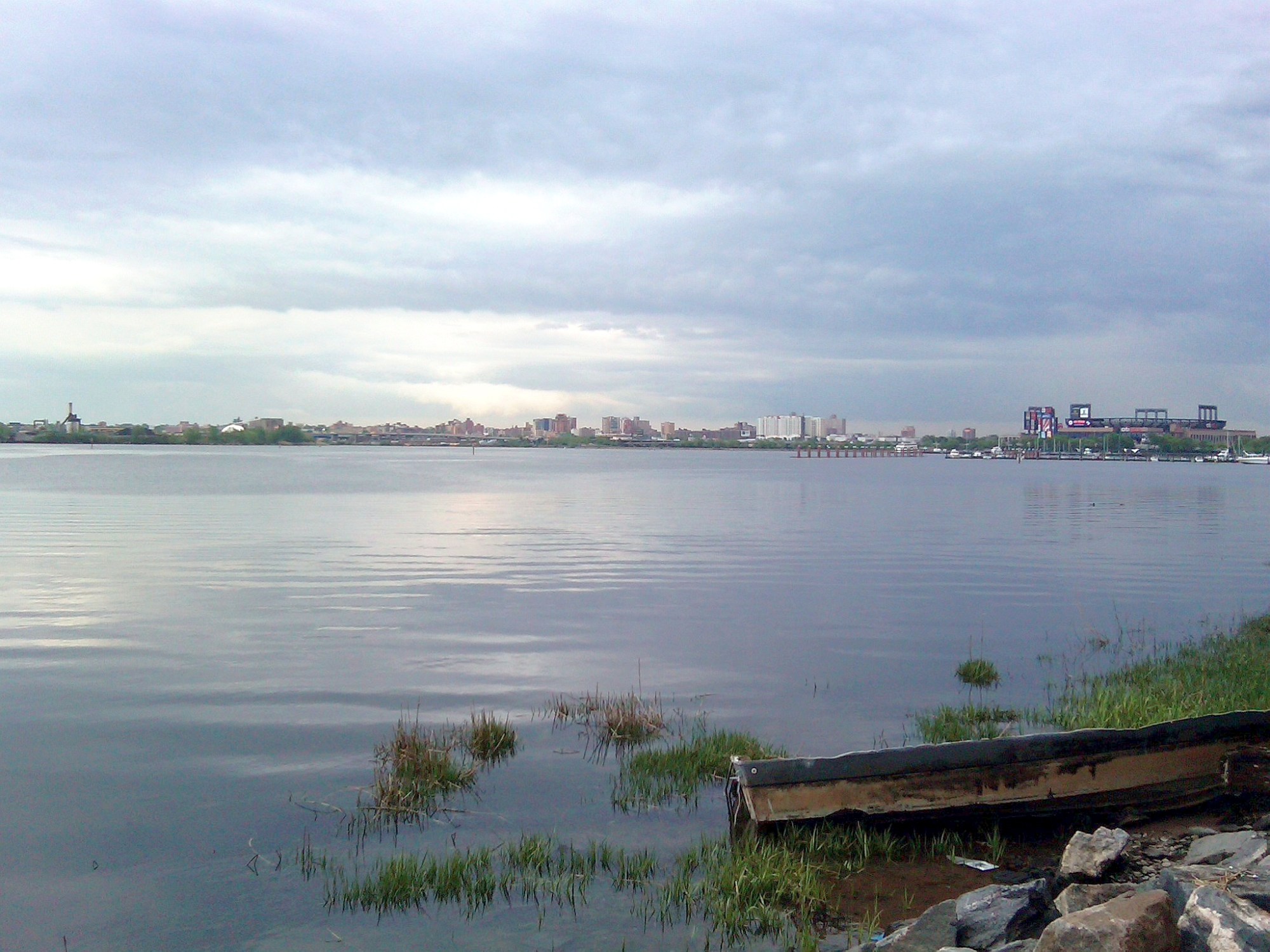 Flushing Bay with NYC in background and cloudy sky above.