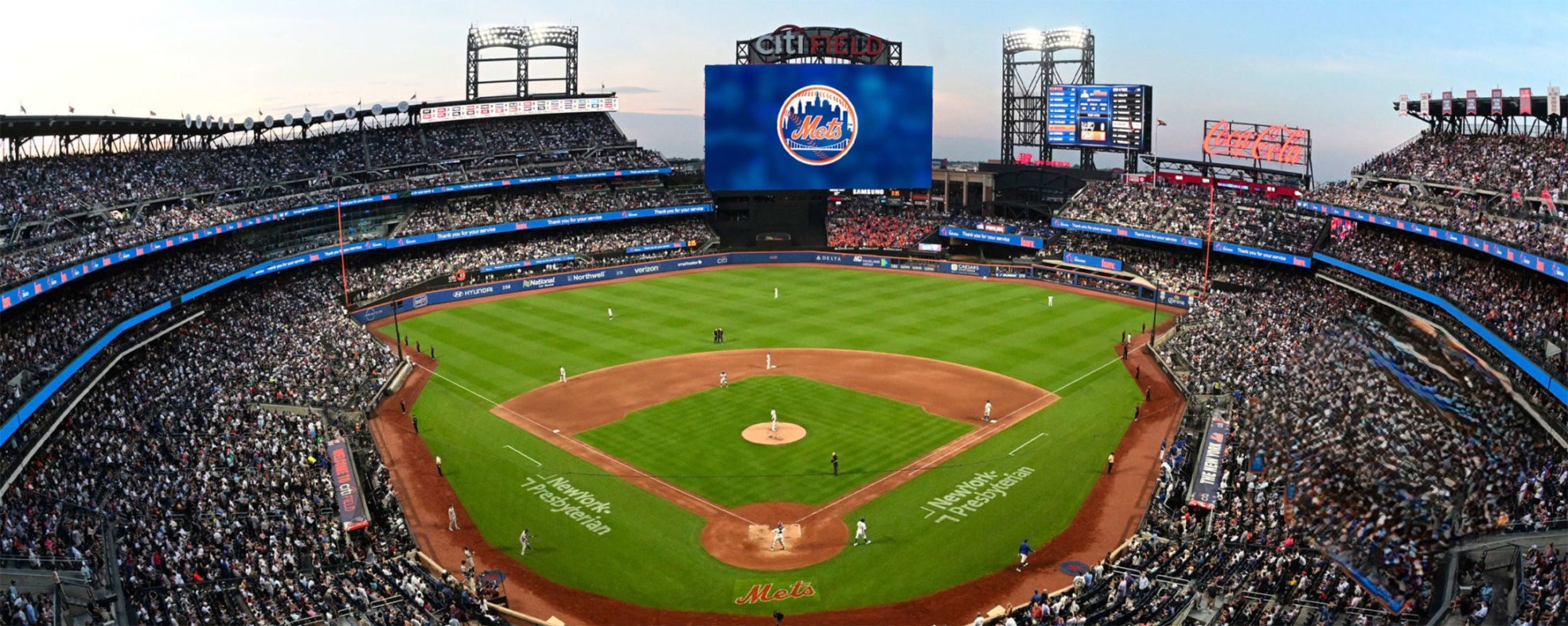 Panoramic view of Citi Field stadium with a New York Mets game in play, large scoreboard displaying the team logo.